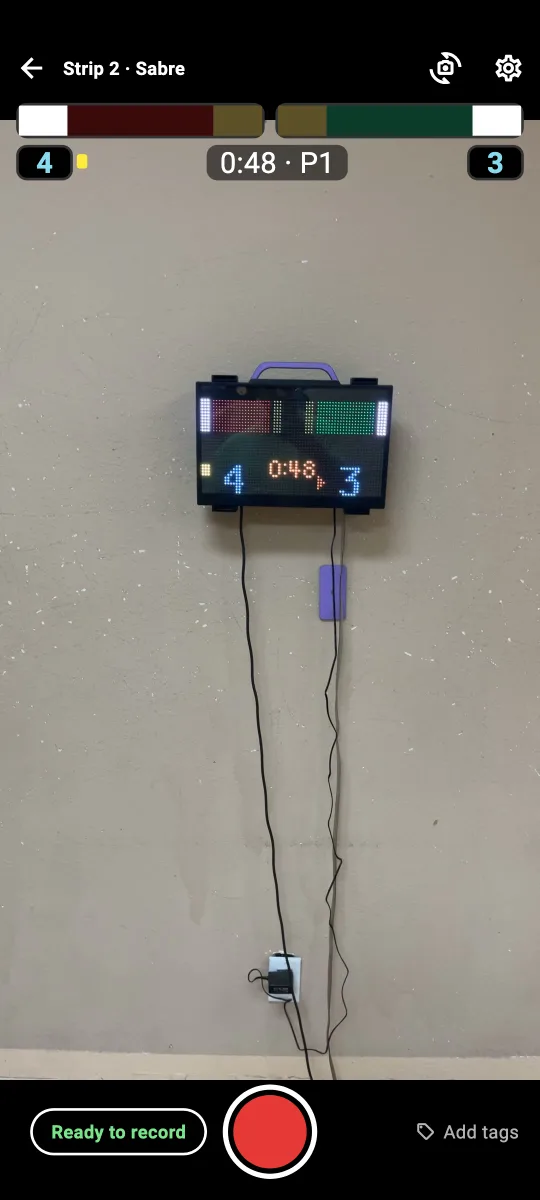 the recording screen: the camera pointed at a scoring box on a wall, with the box's lights, score, and clock overlaid at the top
